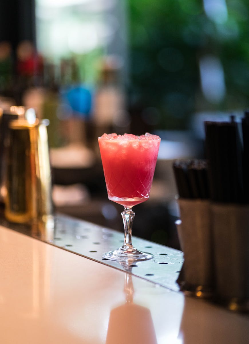 Refreshing cocktail with ice in elegant glass placed on counter in modern bar